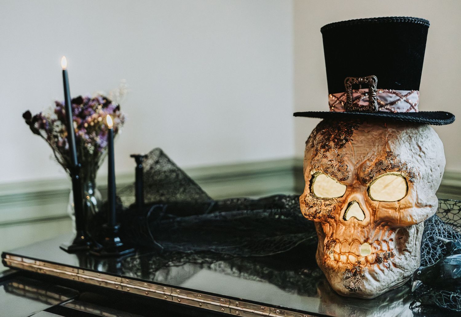 A collection of spooky Halloween decorations including a black top hat, skull, and vintage-style accessories arranged on a surface.