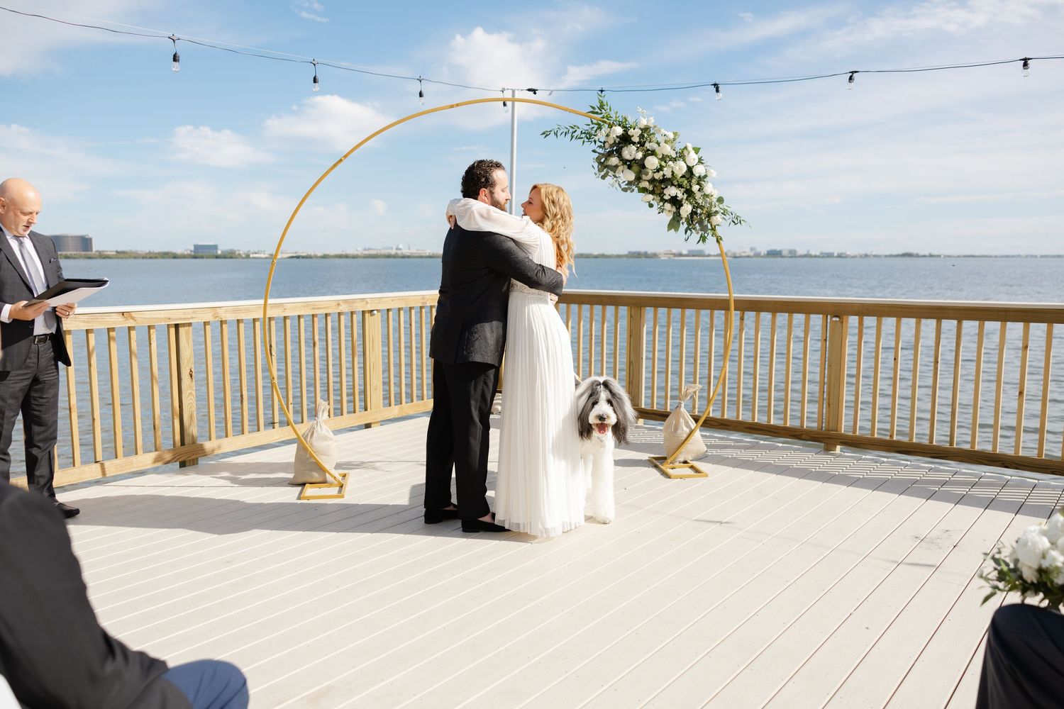 Bride and groom embracing during an outdoor wedding ceremony.