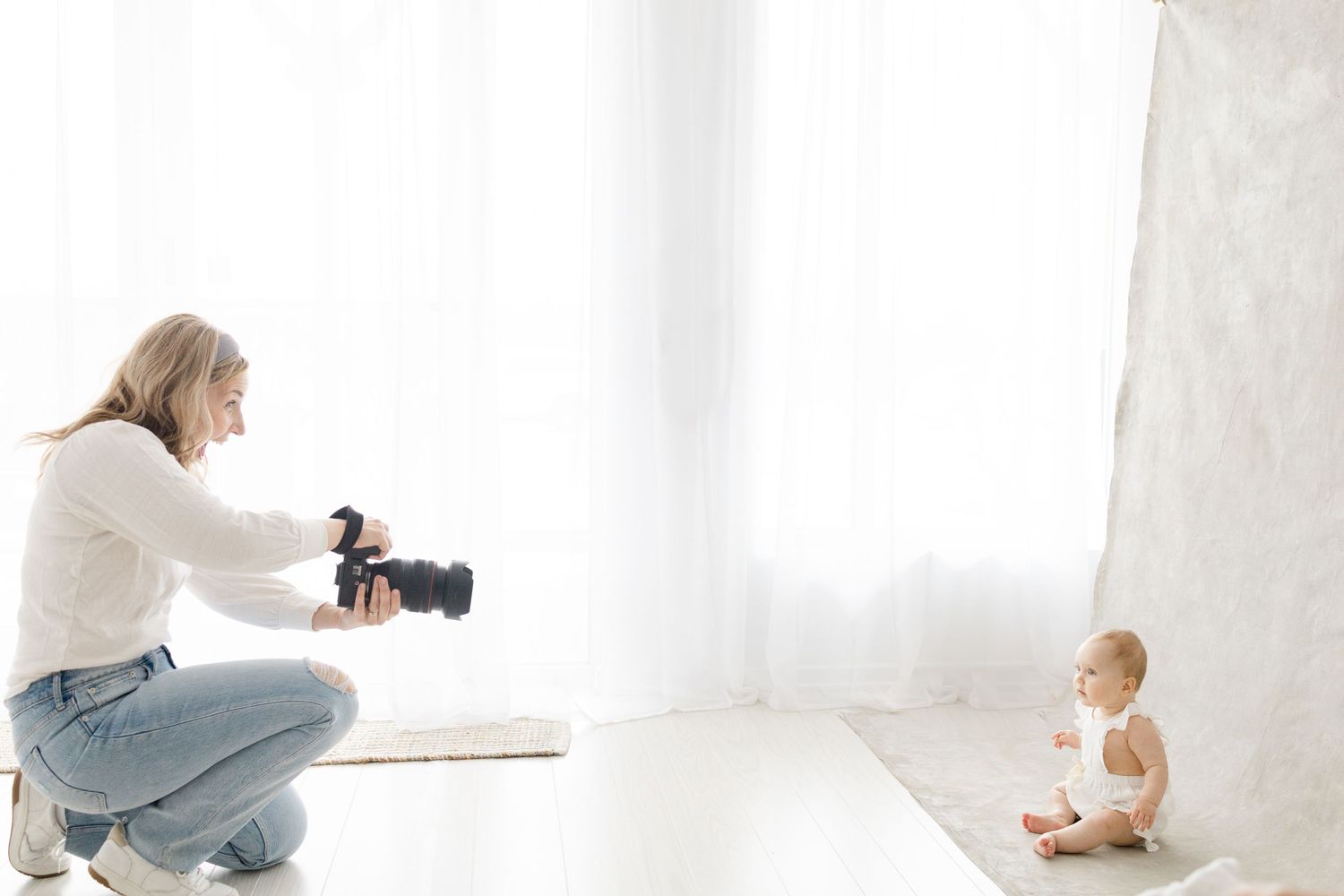 Photographer with camera capturing candid moments in bright white studio.