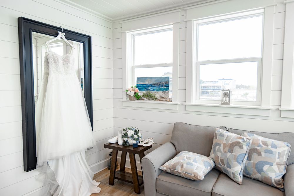 A bright coastal-themed living room features white shiplap walls, large windows, and beach-inspired decor.