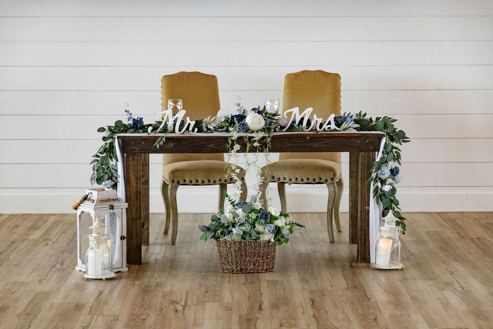 Rustic wooden bench decorated with lanterns and greenery garland for wedding reception decor.