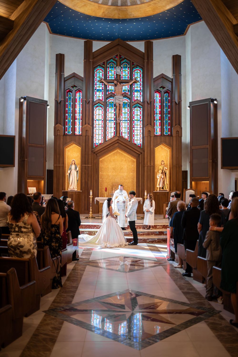 A traditional church wedding ceremony with stained glass windows and elegant lighting illuminating the aisle and altar.