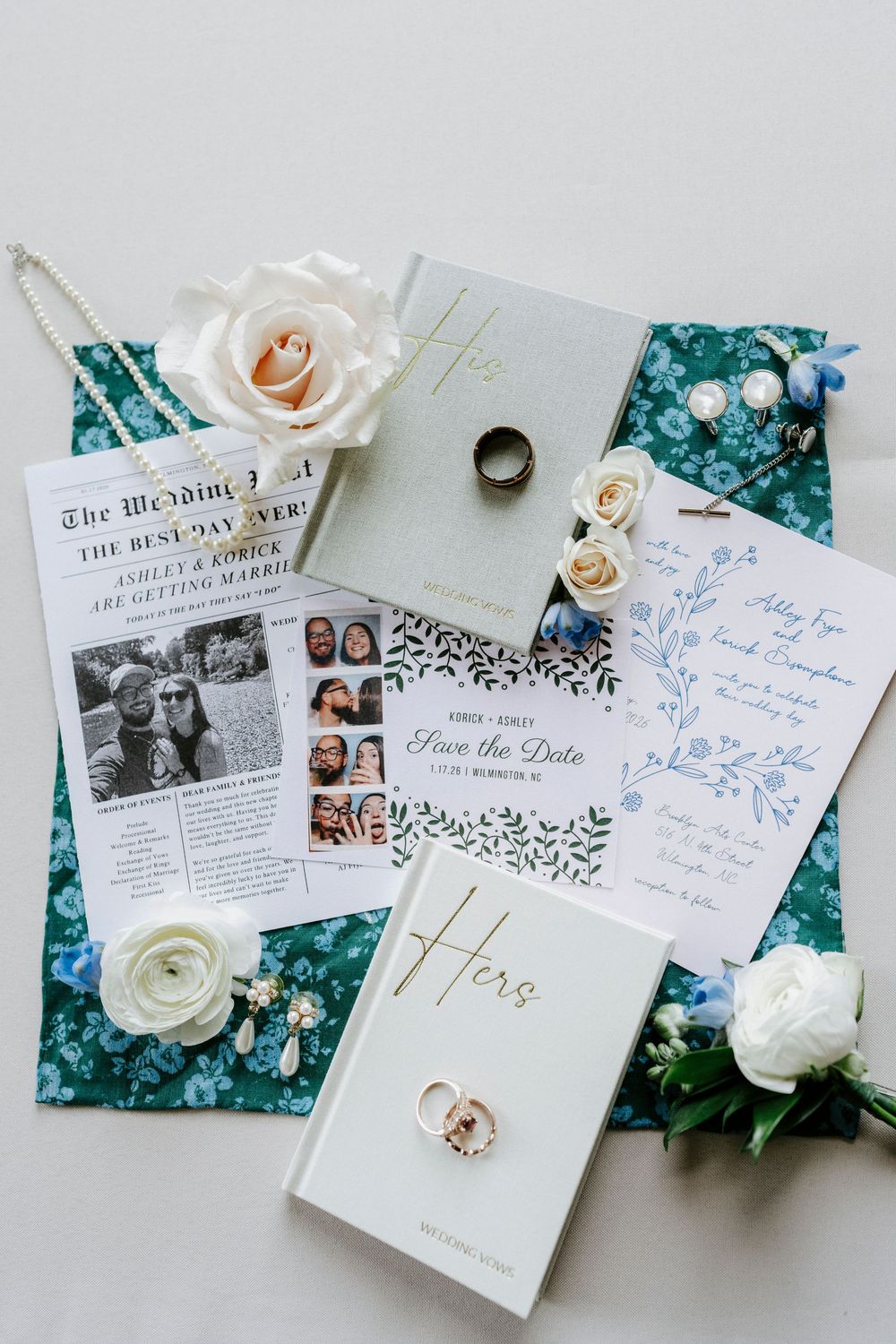Wedding stationery and details including invitations, rings, and white roses arranged on a turquoise background.