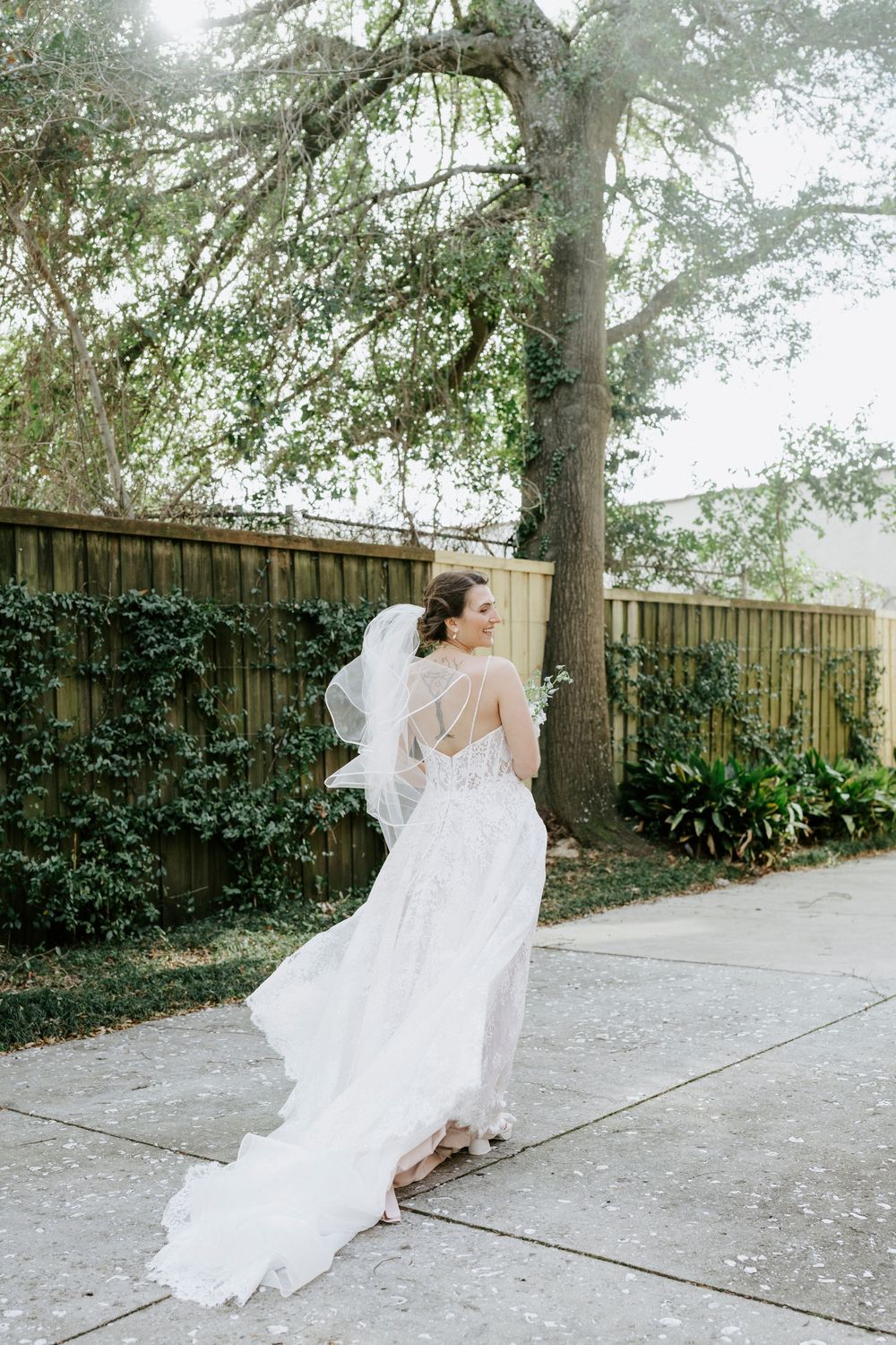 Flowing white wedding dress with delicate details captured in motion against a garden backdrop.