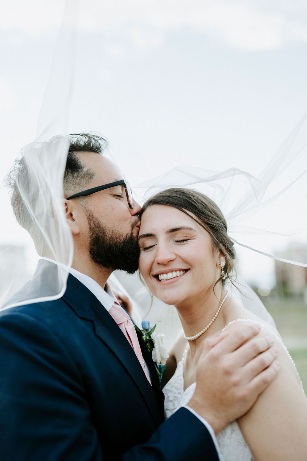 A series of intimate wedding photos showing tender moments between newlyweds under a flowing white veil.