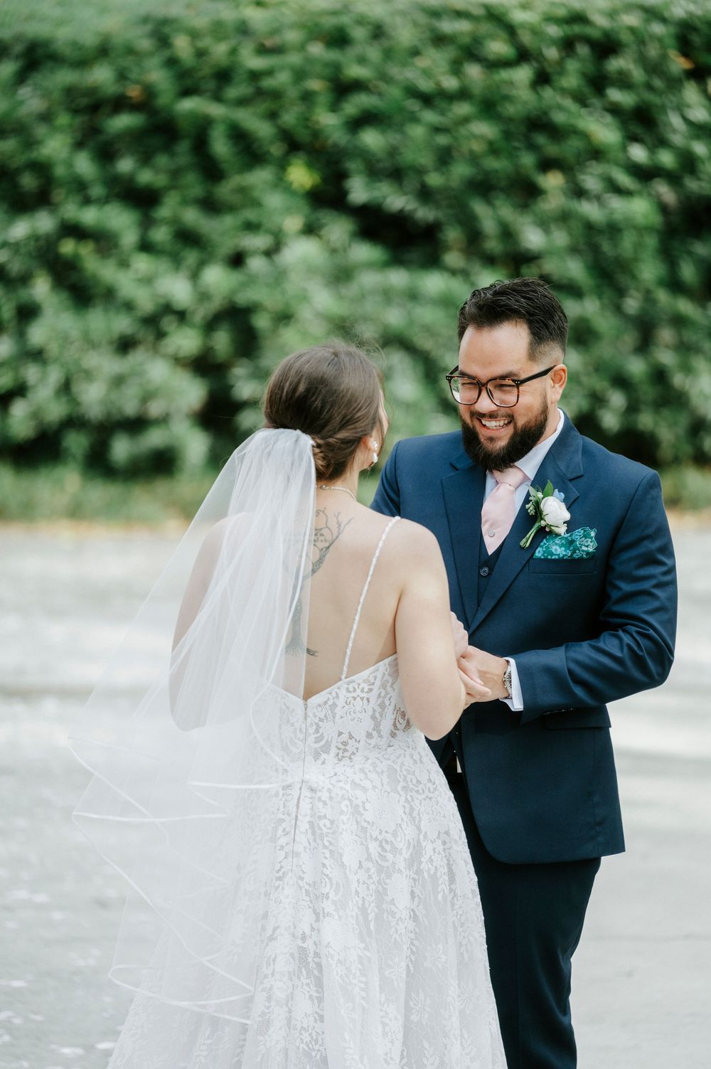 Elegant wedding couple sharing a romantic moment outdoors surrounded by lush greenery.
