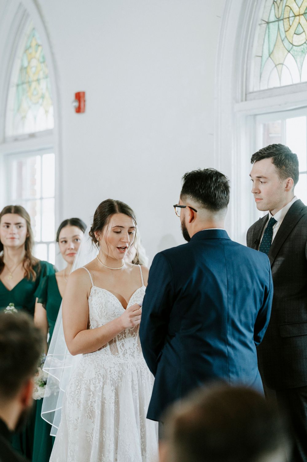 Wedding ceremony in a bright chapel with stained glass windows as guests gather to celebrate the occasion.