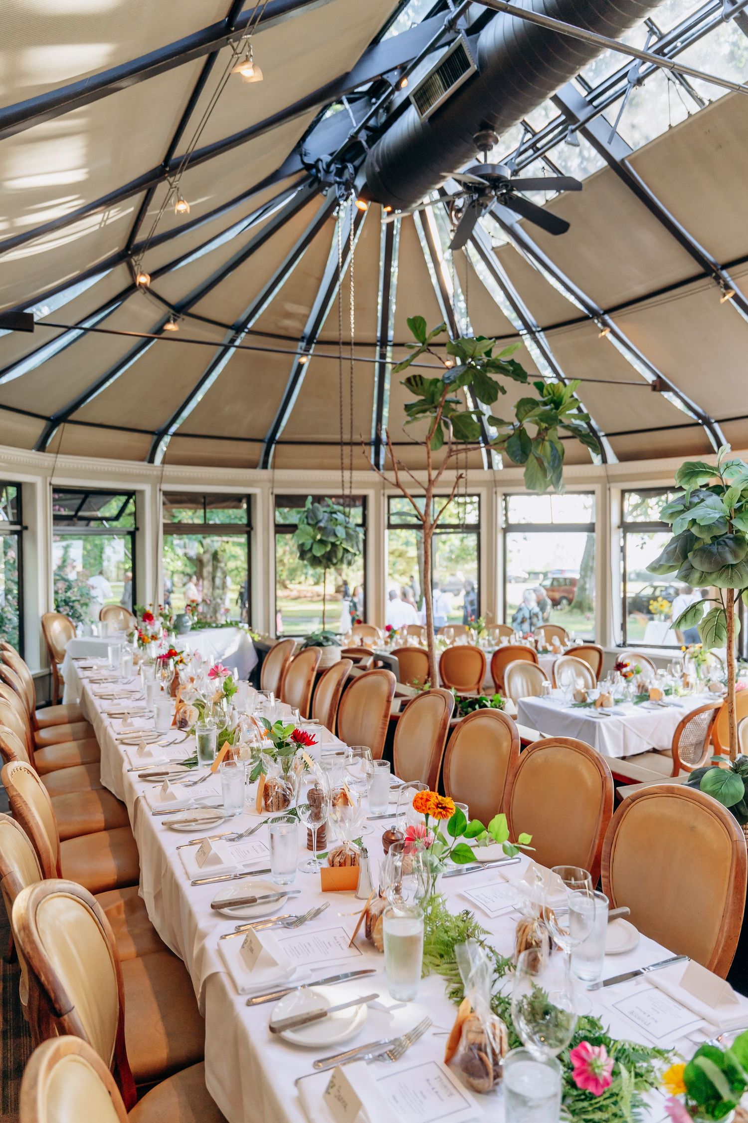 Elegant restaurant dining room with circular glass ceiling and tables set with white linens and floral centerpieces.