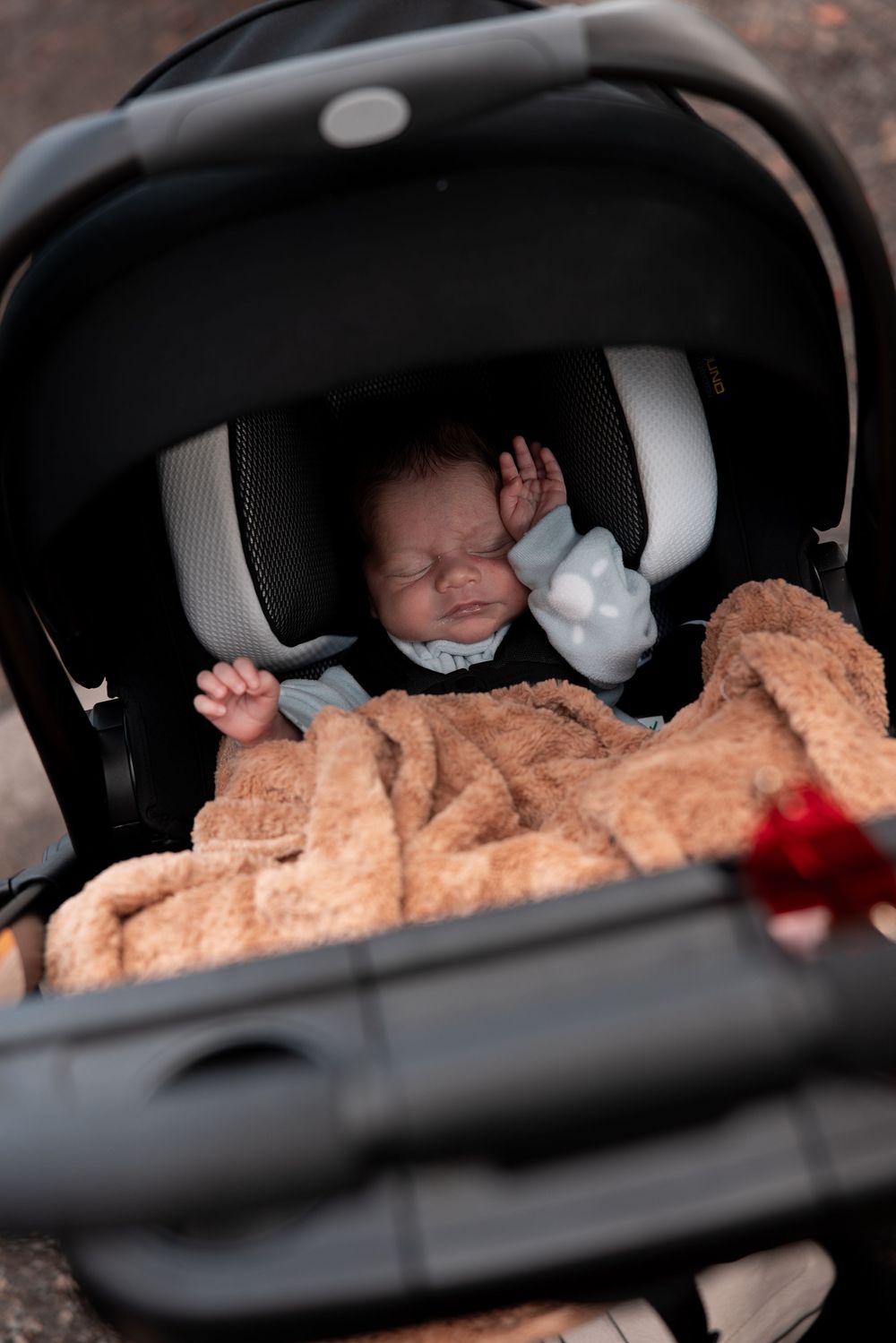 A series of four photos showing someone sleeping peacefully in a car seat with a plush brown blanket.