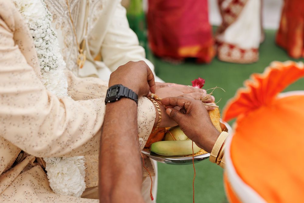Hands serving and preparing food on plates at an outdoor event with colorful table settings.