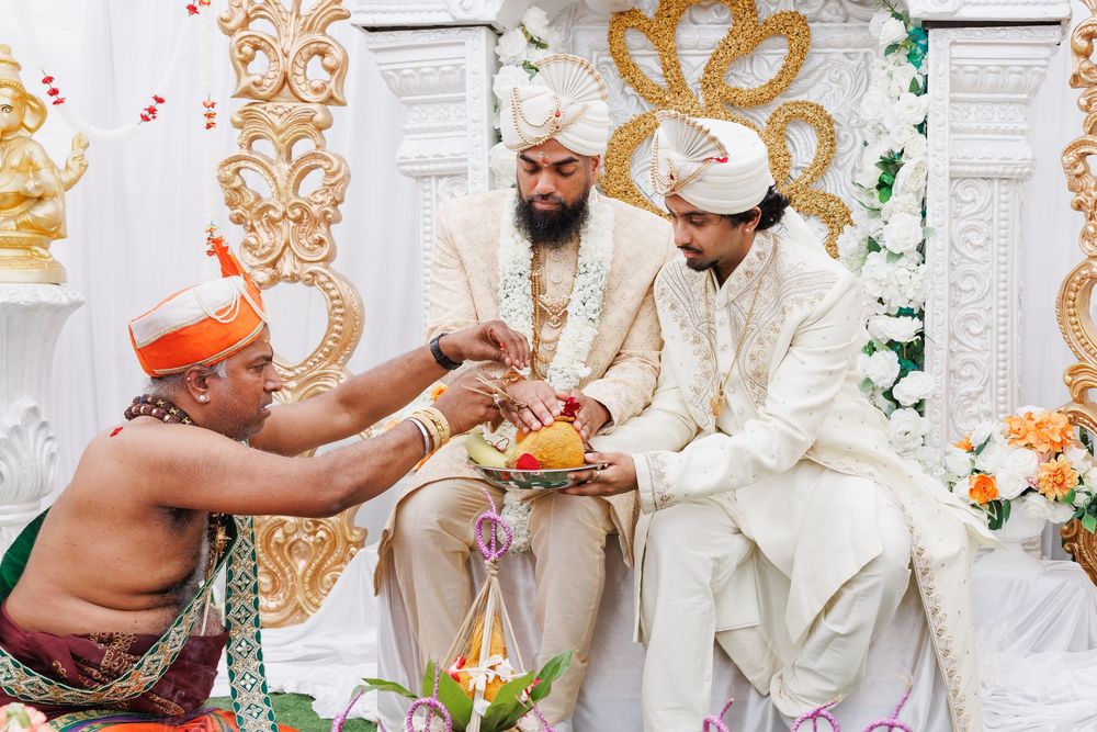 Traditional Indian wedding ceremony with ritual offerings being exchanged between participants on decorated stage.