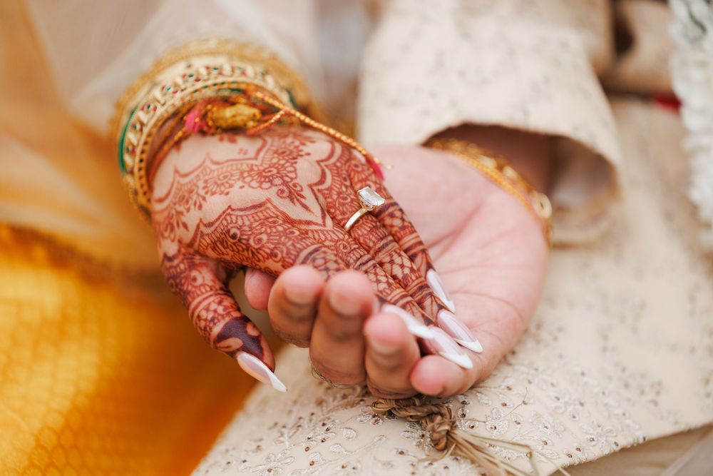 Close-up of hands with intricate henna designs during wedding ceremony.