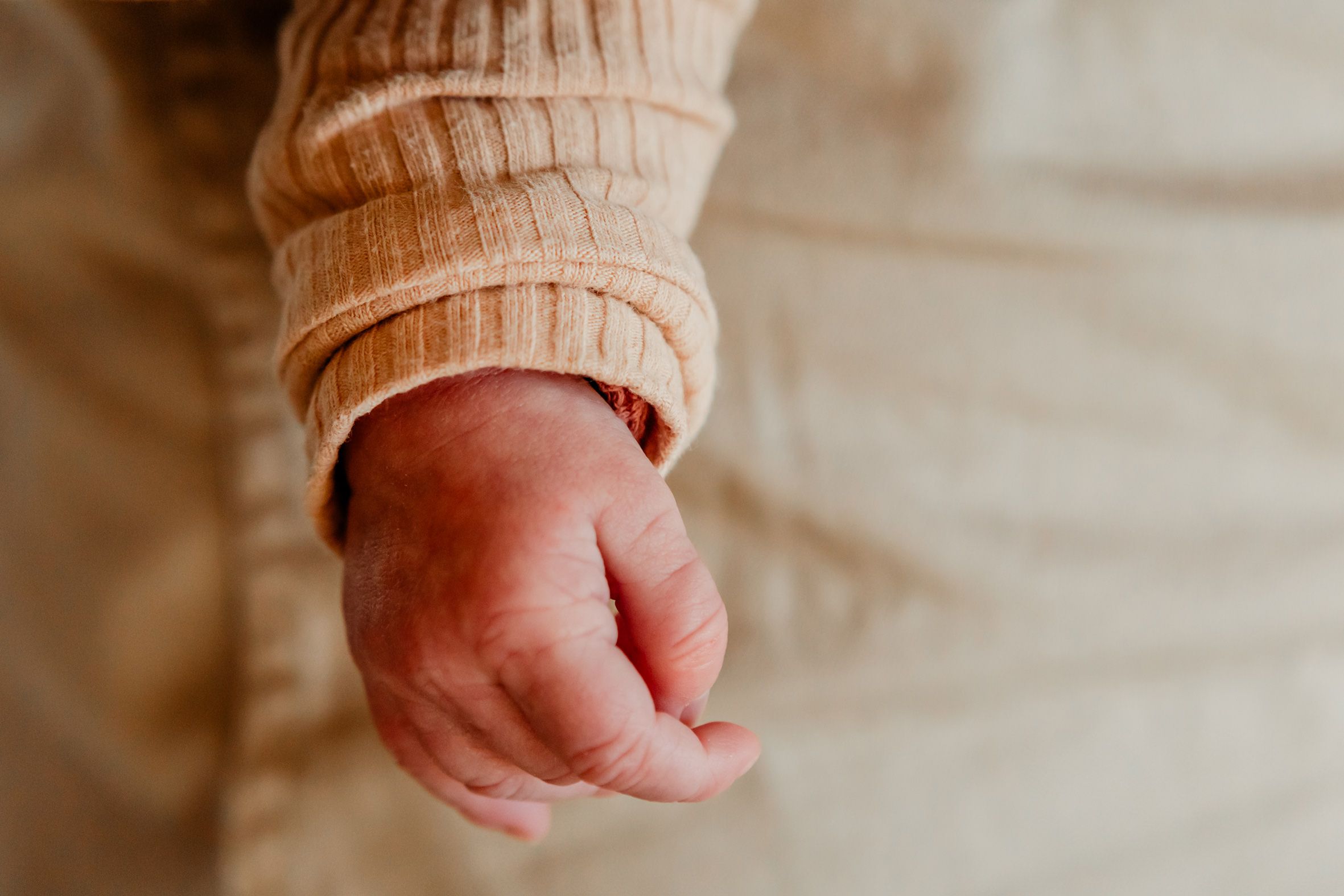Close-up van een babyhandje tijdens een lifestyle newbornshoot, vastgelegd in een rustig en liefdevol moment