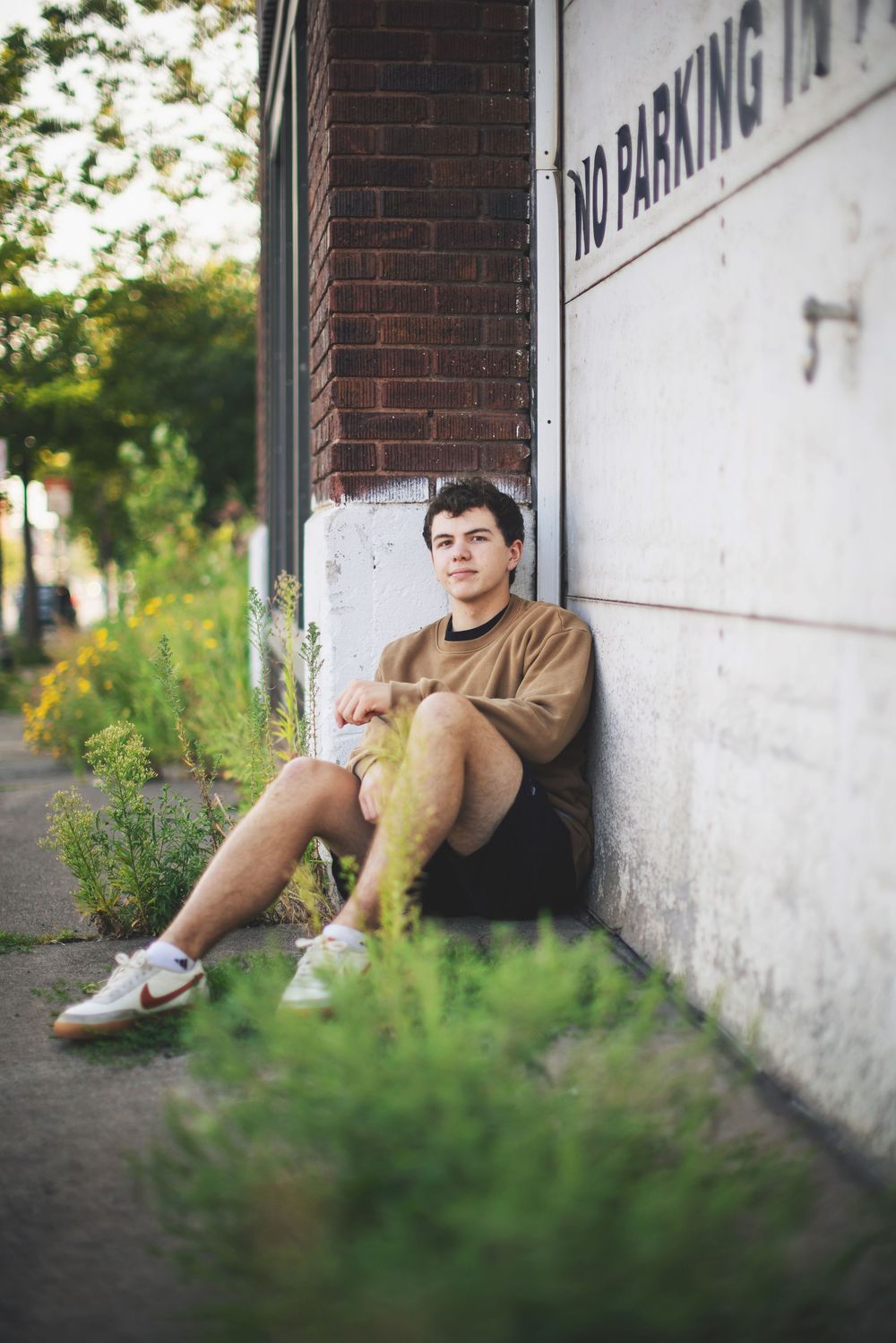 Person resting against brick wall with white paint in outdoor urban setting.