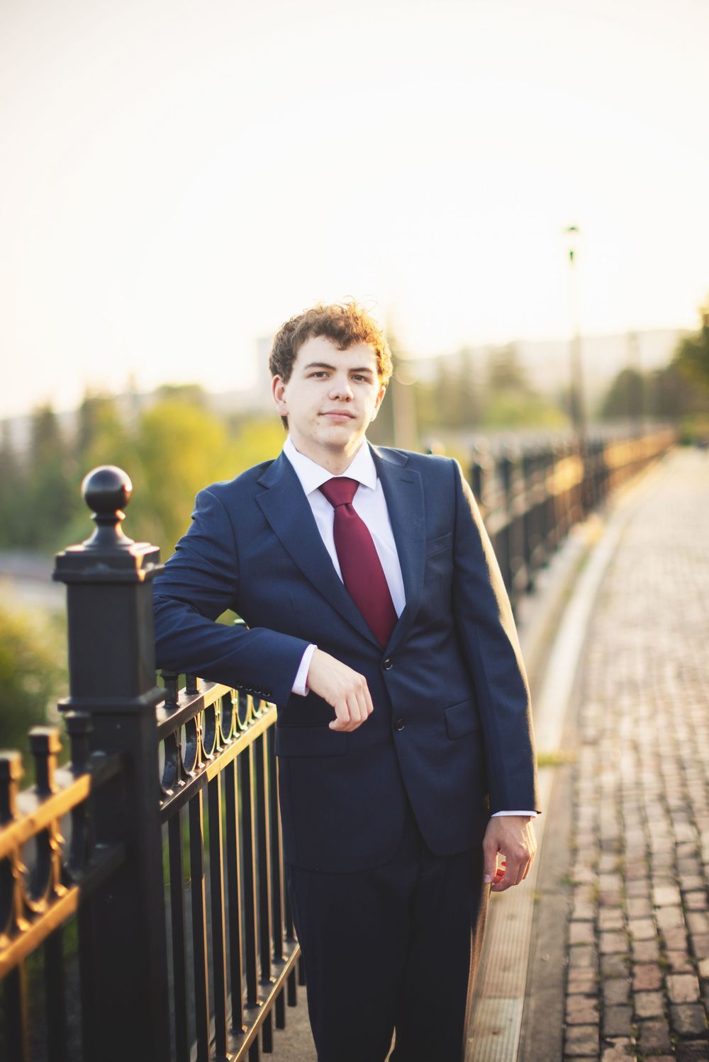 Formal portrait series along brick walkway with iron railing during golden hour.