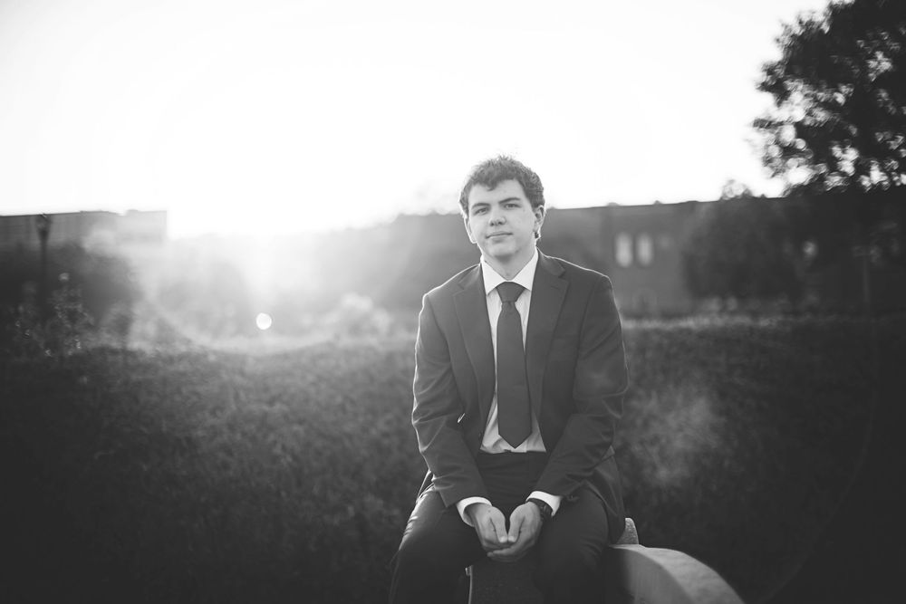 High School Senior  in backlit field during golden hour creating dramatic lighting effect.