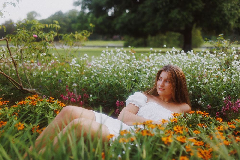A dreamy outdoor photoshoot in a garden with orange marigolds and white wildflowers in bloom.