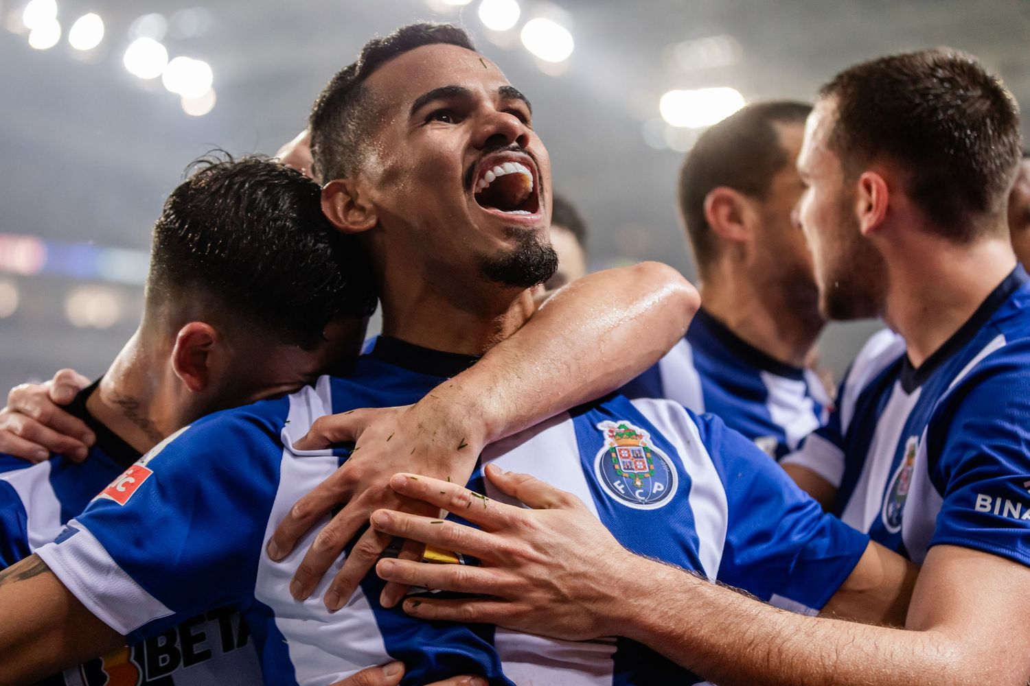 Soccer players in blue and white jerseys celebrating a goal with intense emotion.