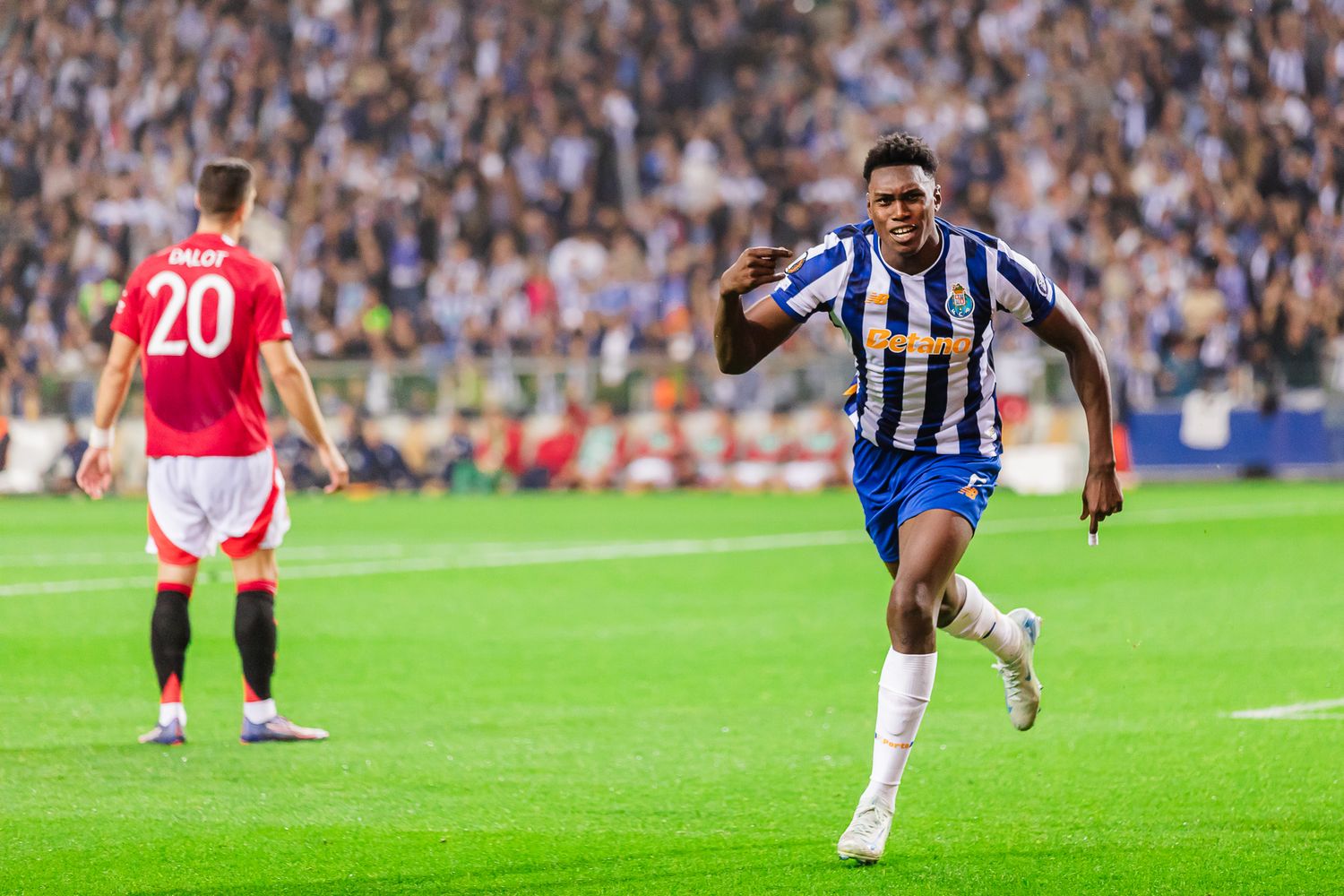 Soccer player celebrating on field in striped jersey during intense match.