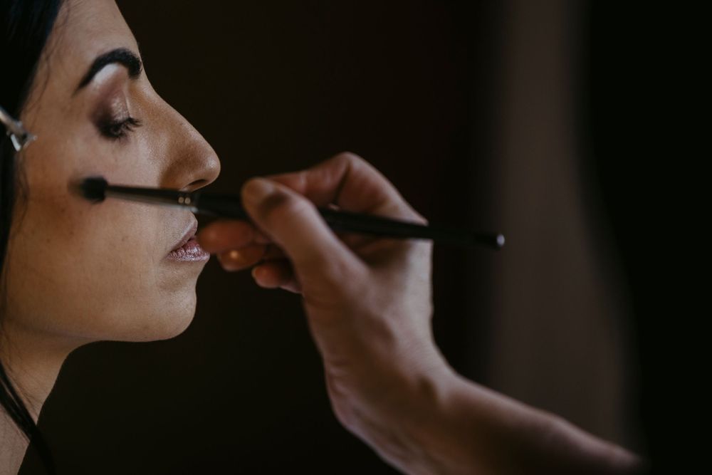 Close-up shot of makeup application with a brush in dramatic lighting.