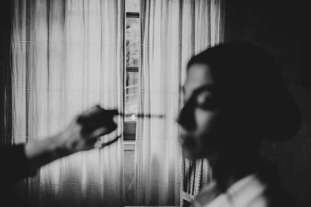 Silhouette figure standing by window with sheer curtains in black and white.