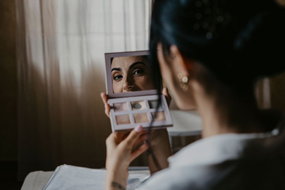 A person getting ready for a wedding holds a phone while wearing a white robe.