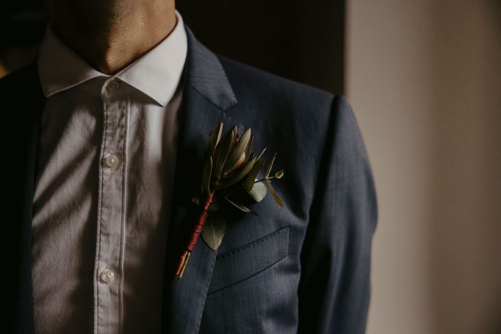 Close-up detail of a navy blue wedding suit with boutonniere.