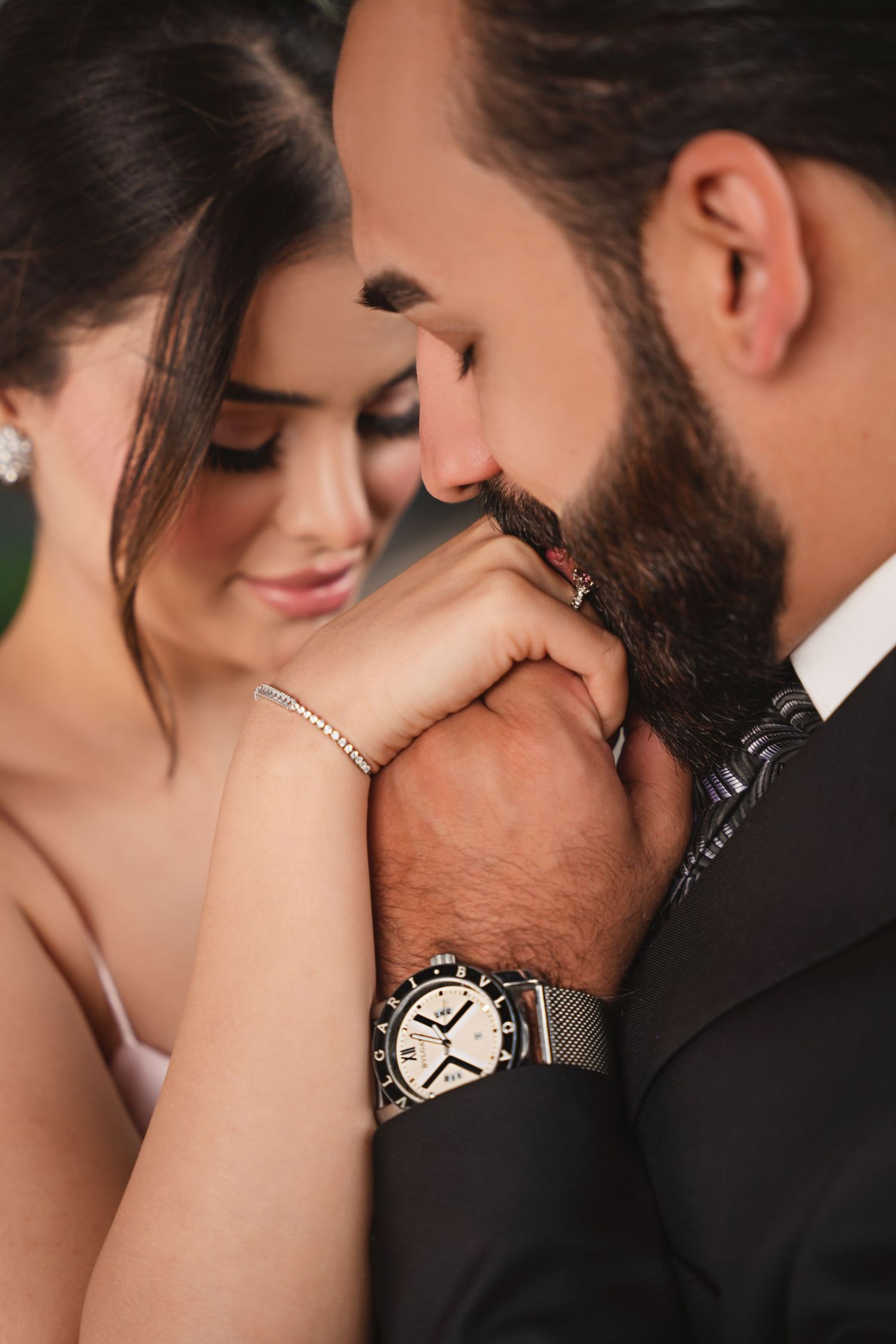 Intimate close-up photo showing a tender moment with jewelry details including a bracelet and elegant wristwatch.