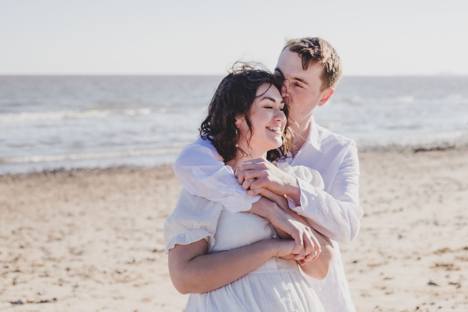 A couple shares an intimate moment of laughter together on a sunny beach.
Couple photography, Suffolk coast