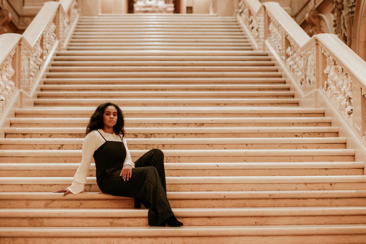 Elegant grand marble staircase with ornate decorative railings in warm lighting.