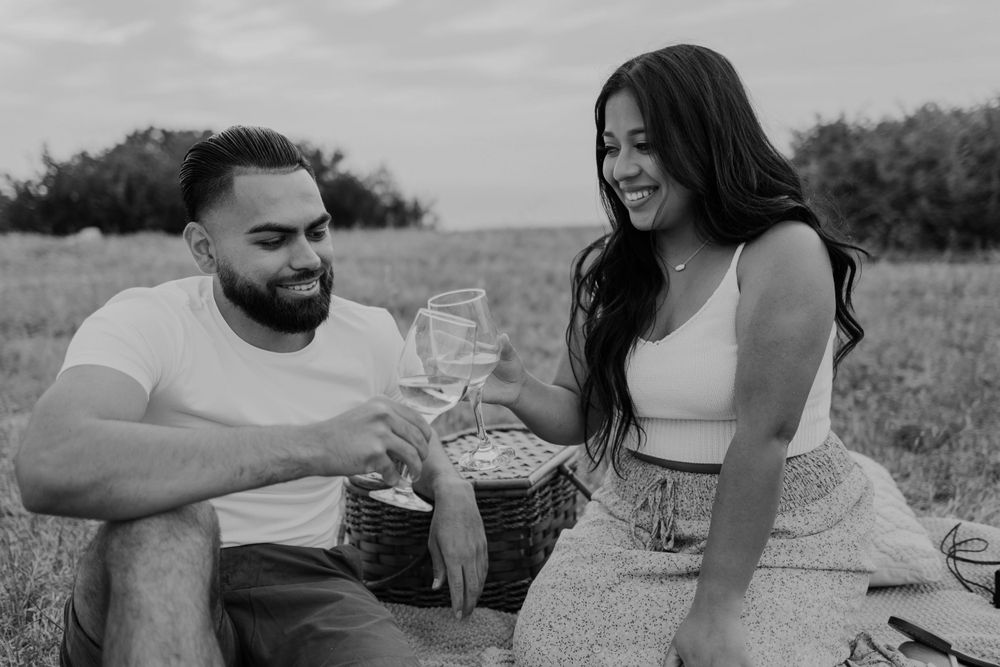 Happy couple having wine and sharing laughter during an outdoor picnic.