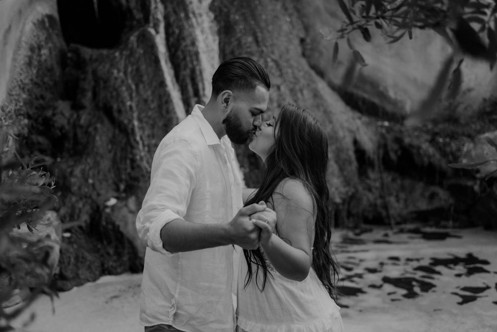 Romantic couple embracing near rocky cliffs in black and white photography.