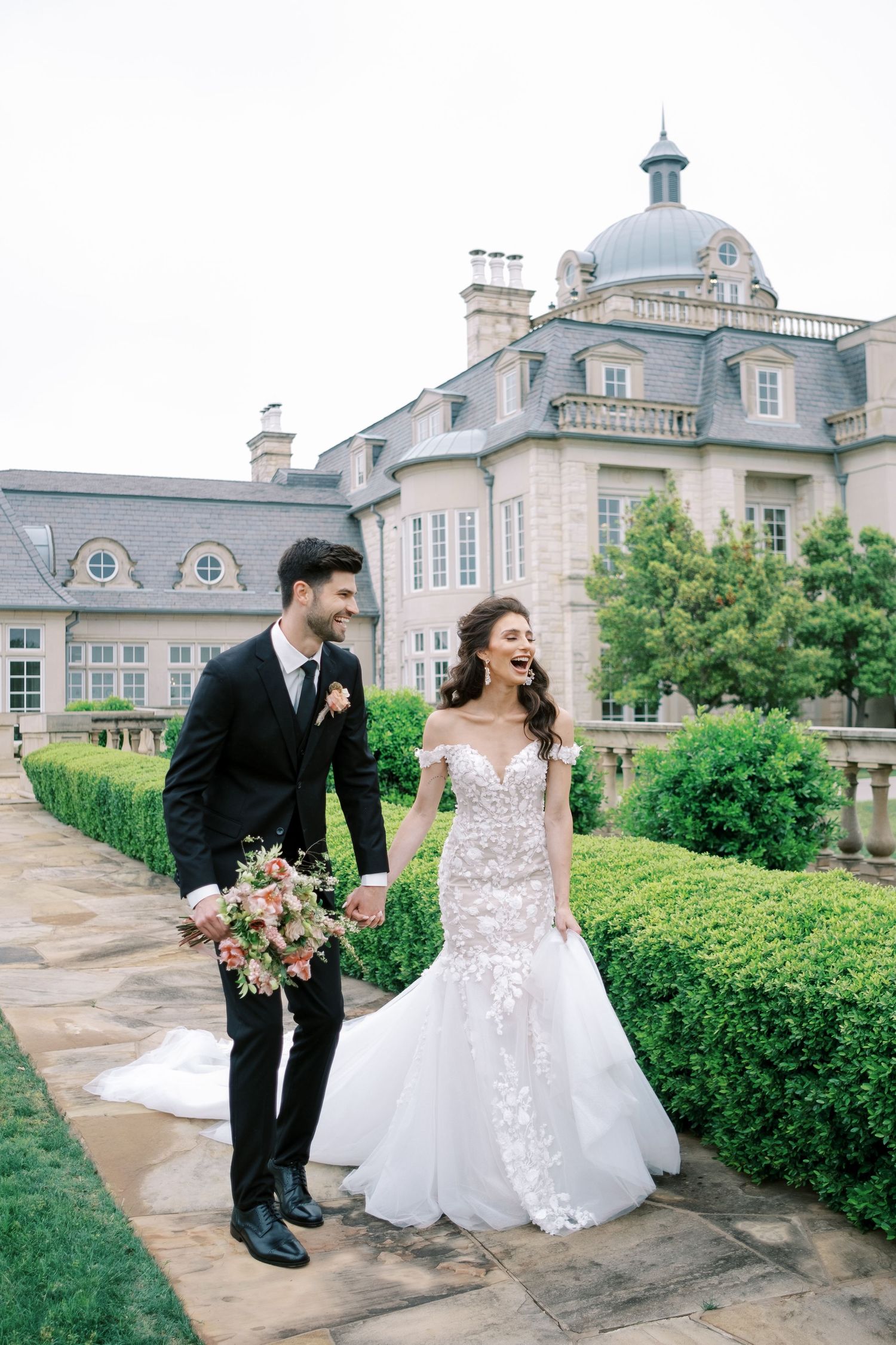 Elegant couple shares joyful moment outside grand estate with blue domed architecture.