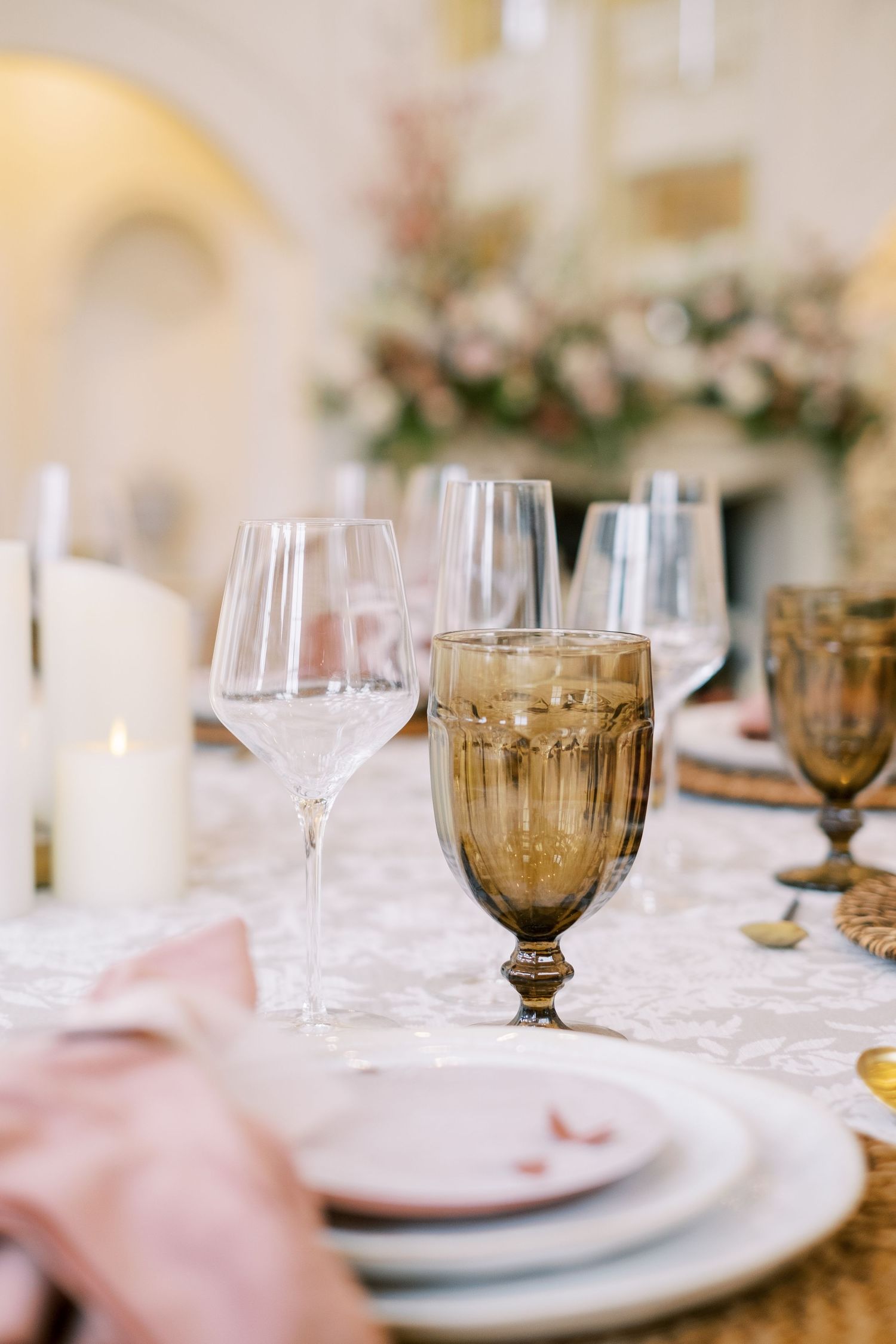 Elegant table setting with amber glassware and white plates on lace tablecloth.