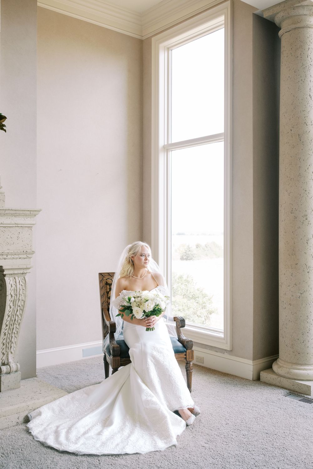 Elegant bridal portrait in spacious room with large windows and classical columns.