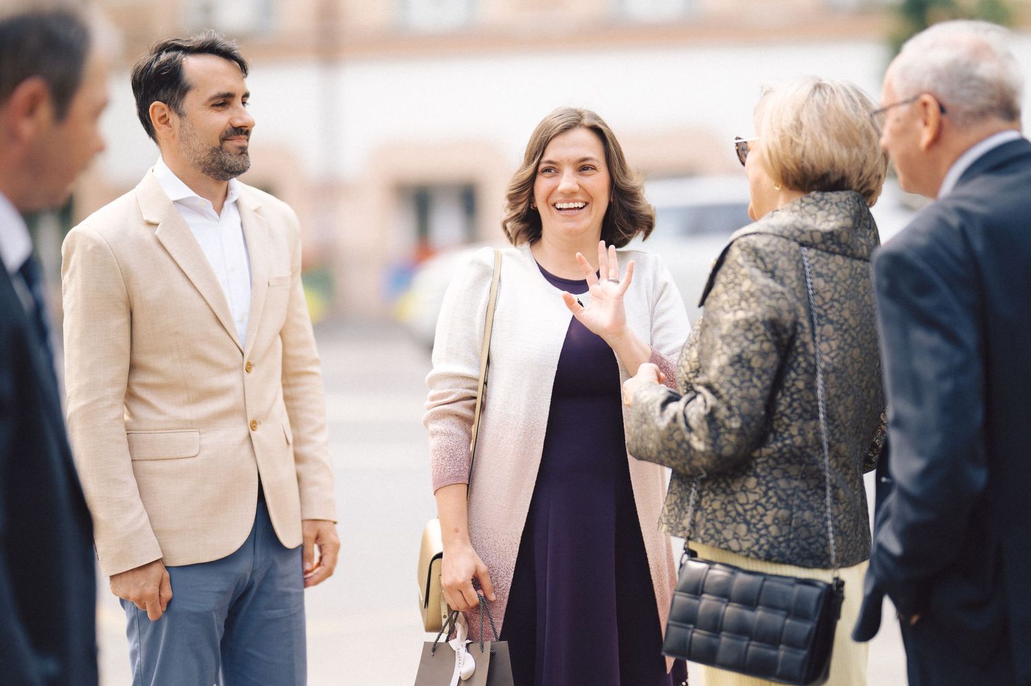 A small group of professionals having an animated conversation outdoors in business attire.
