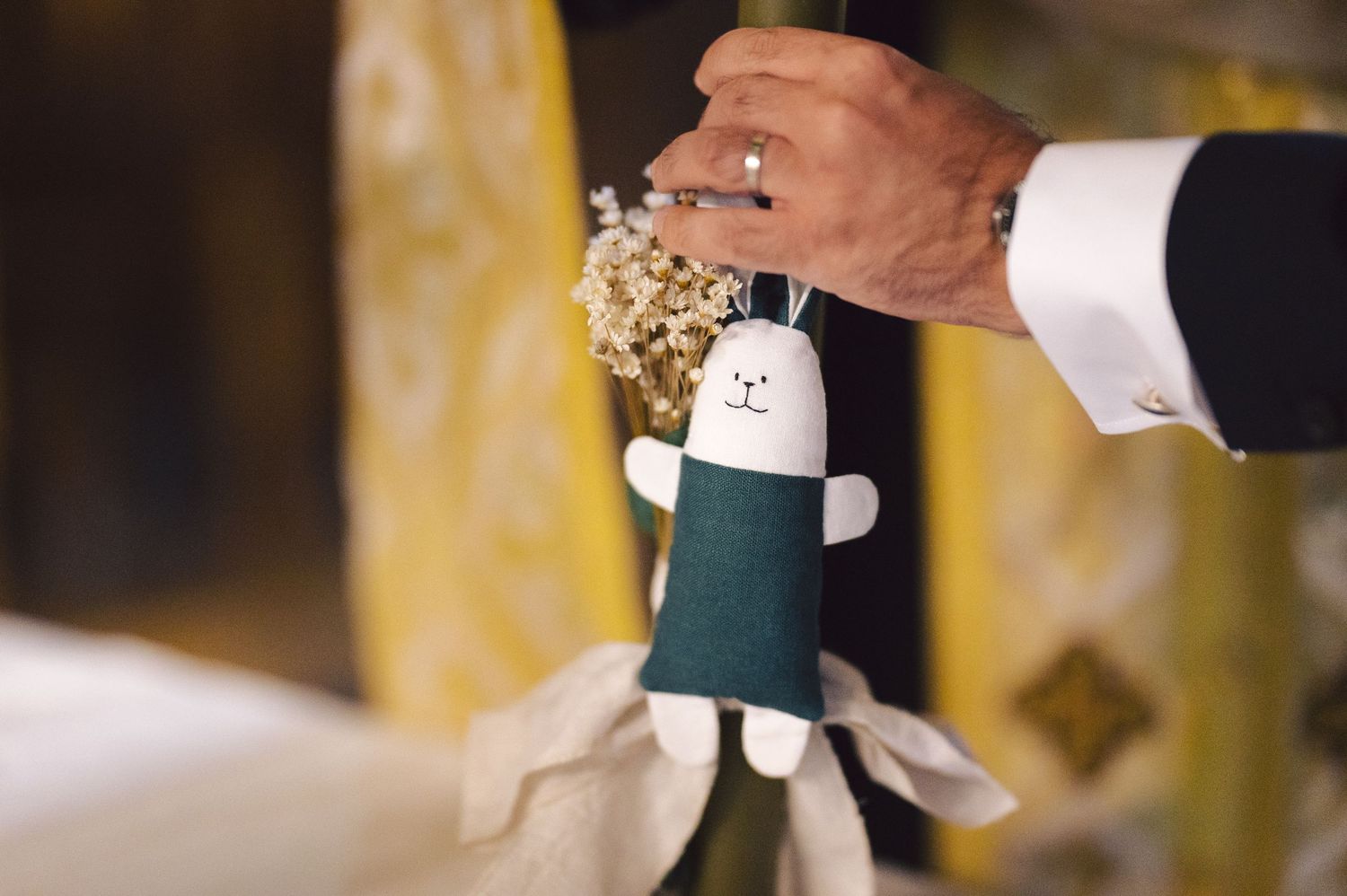 A person's hand pops open a champagne bottle wrapped in a decorative cover at a celebration.
