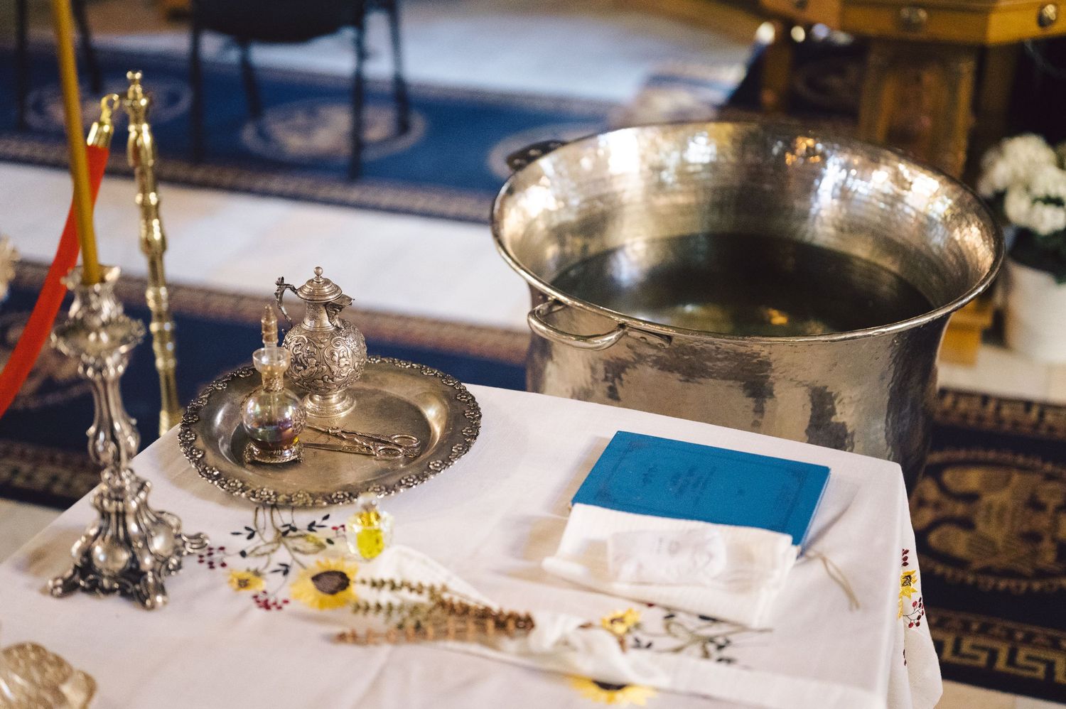 Religious ceremonial items including a chalice, incense burner, and holy book arranged on white altar cloth.