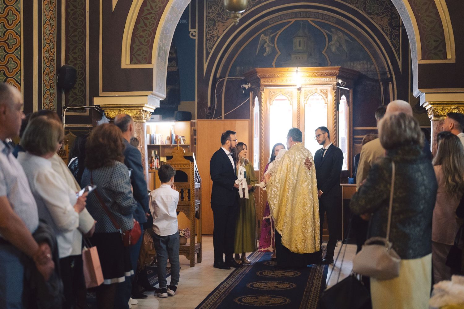Religious ceremony taking place in ornate church interior with clergy in gold robes and congregation gathering.