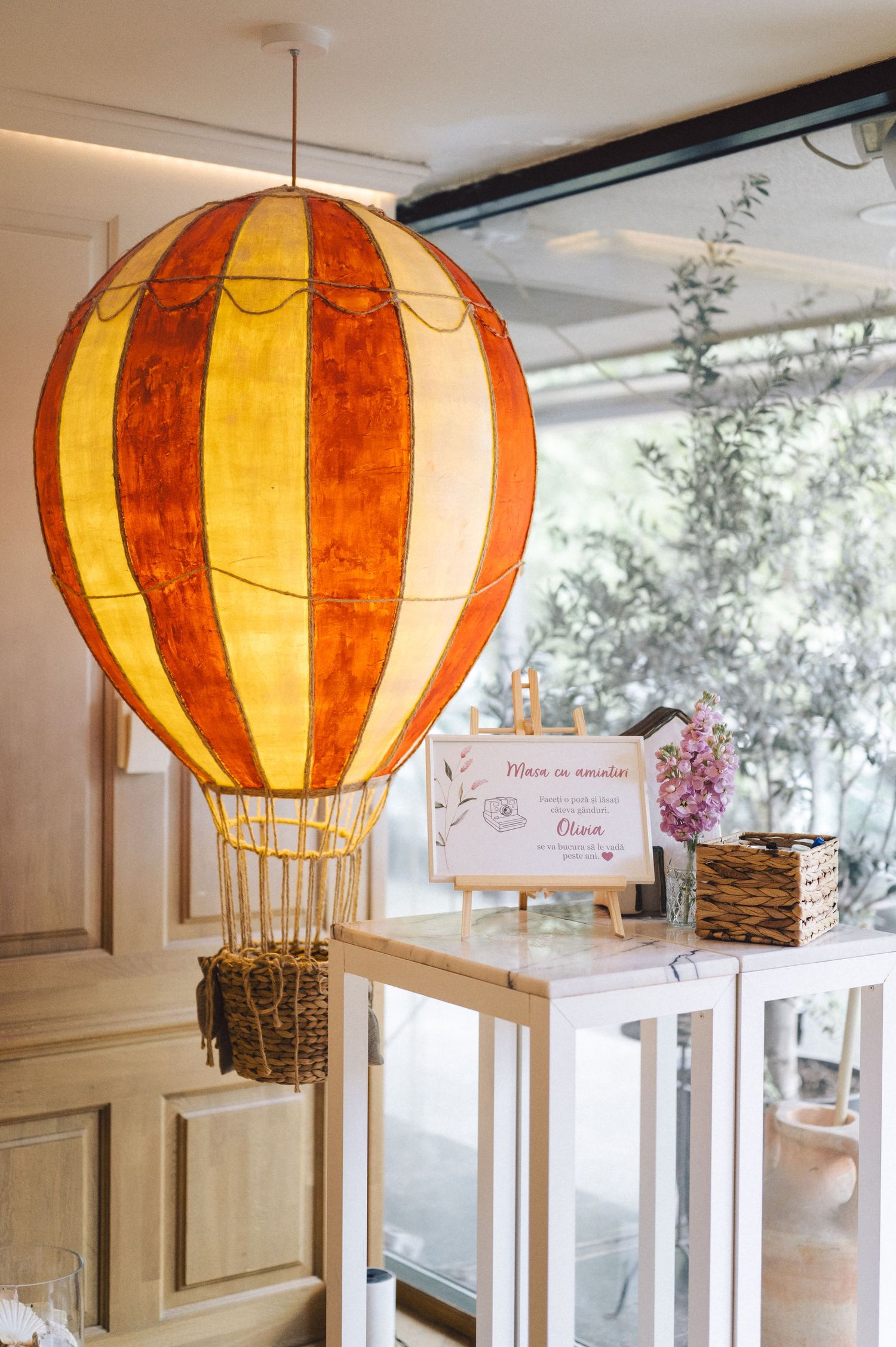 Illuminated orange and yellow paper hot air balloon lamp hangs from ceiling next to whitewashed decor.