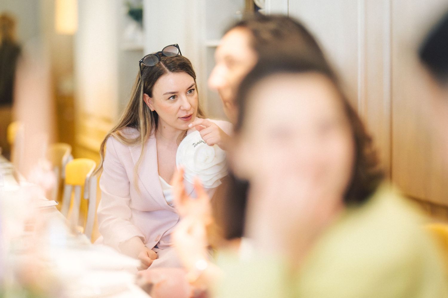 A person listens attentively during a discussion in a bright interior setting with sunlit atmosphere.