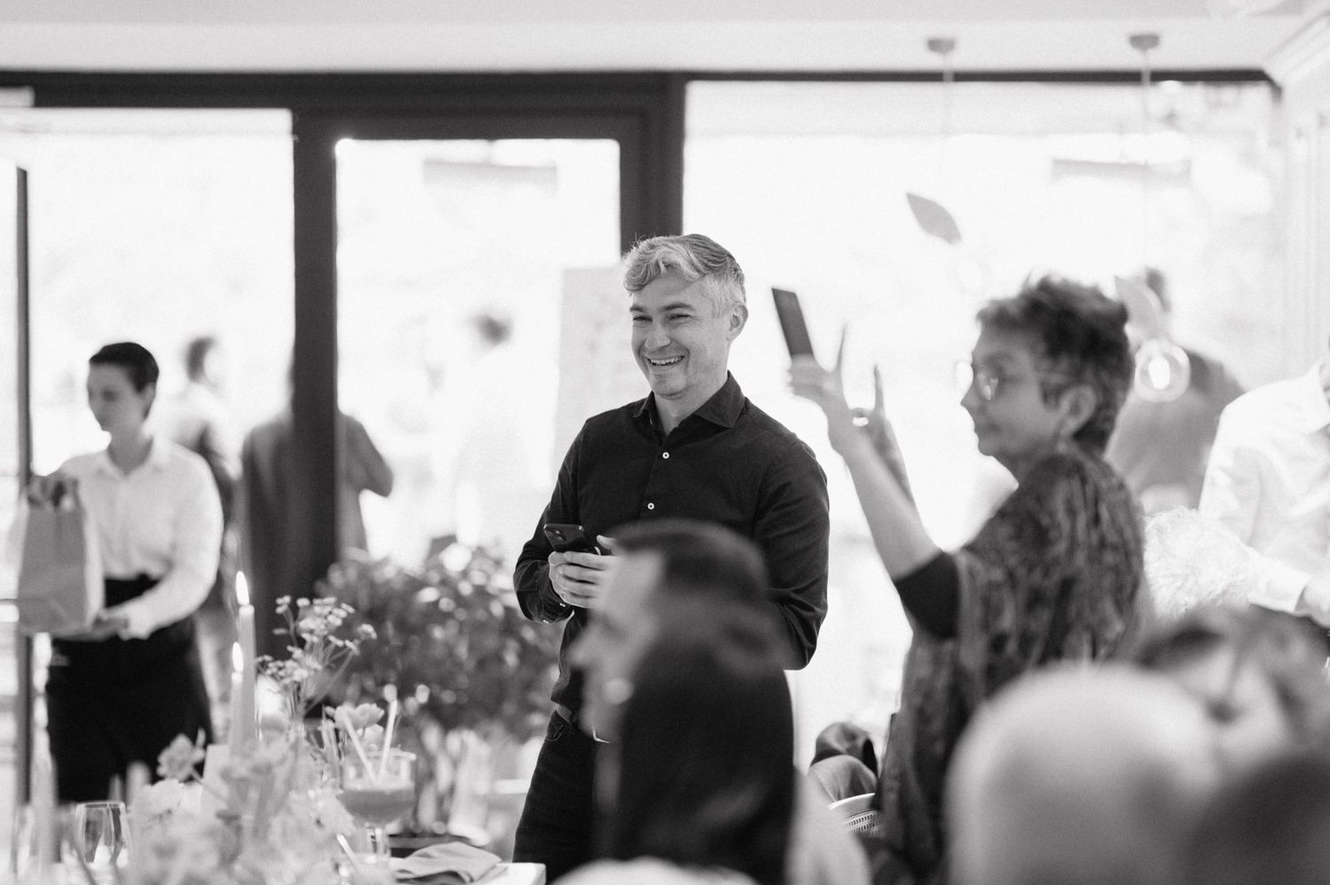 Black and white photograph of guests during a celebration event in a banquet hall setting.