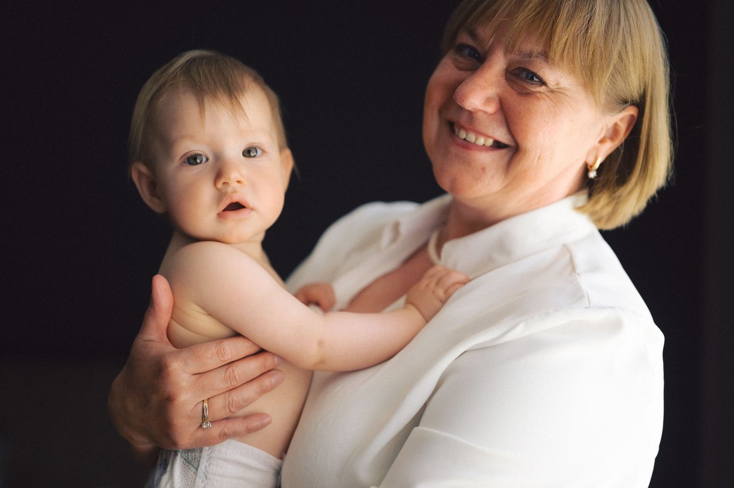 A loving portrait on black background featuring gentle expressions and light-colored attire.