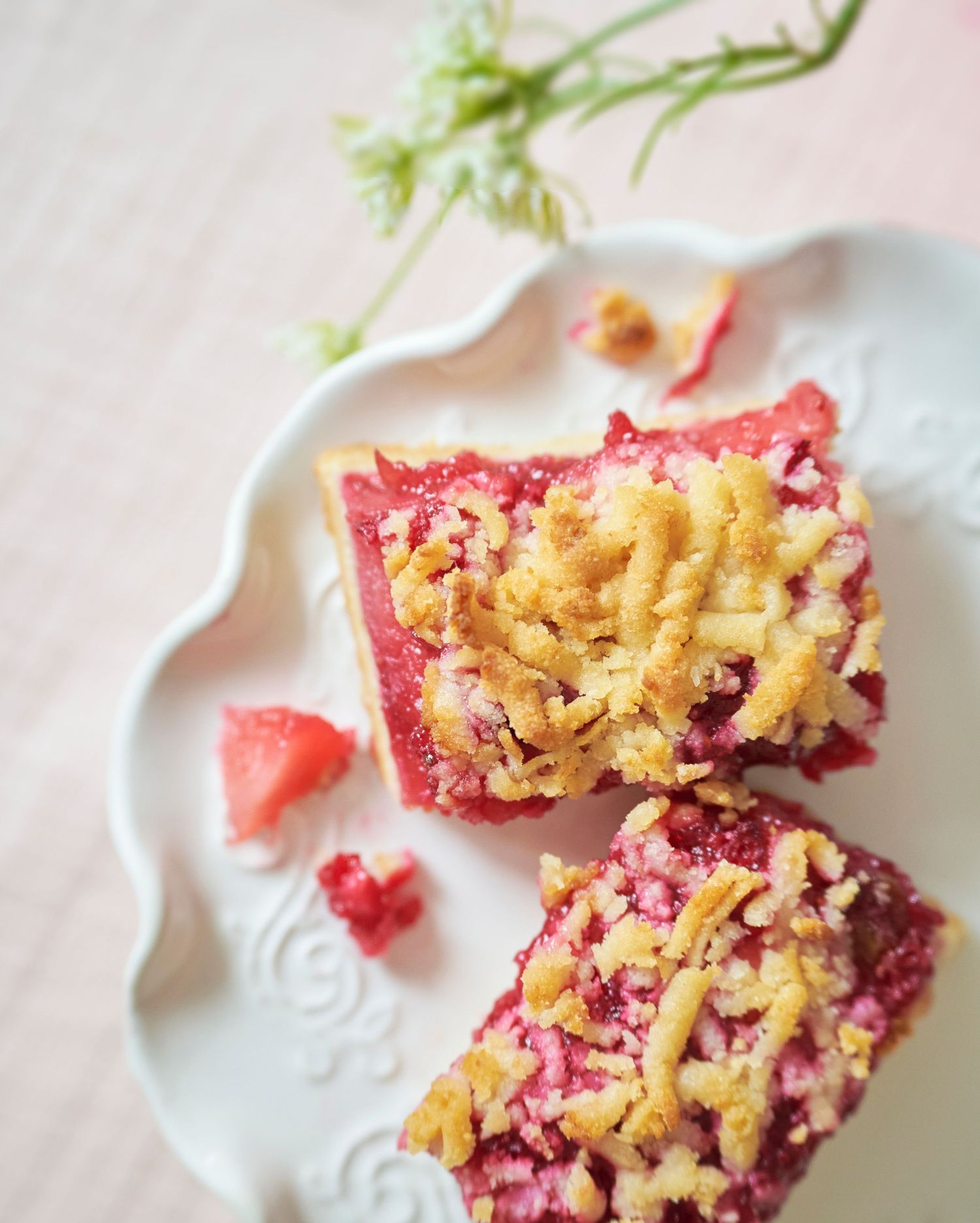 Sliced raspberry crumble bars with buttery streusel topping served on an elegant white plate.