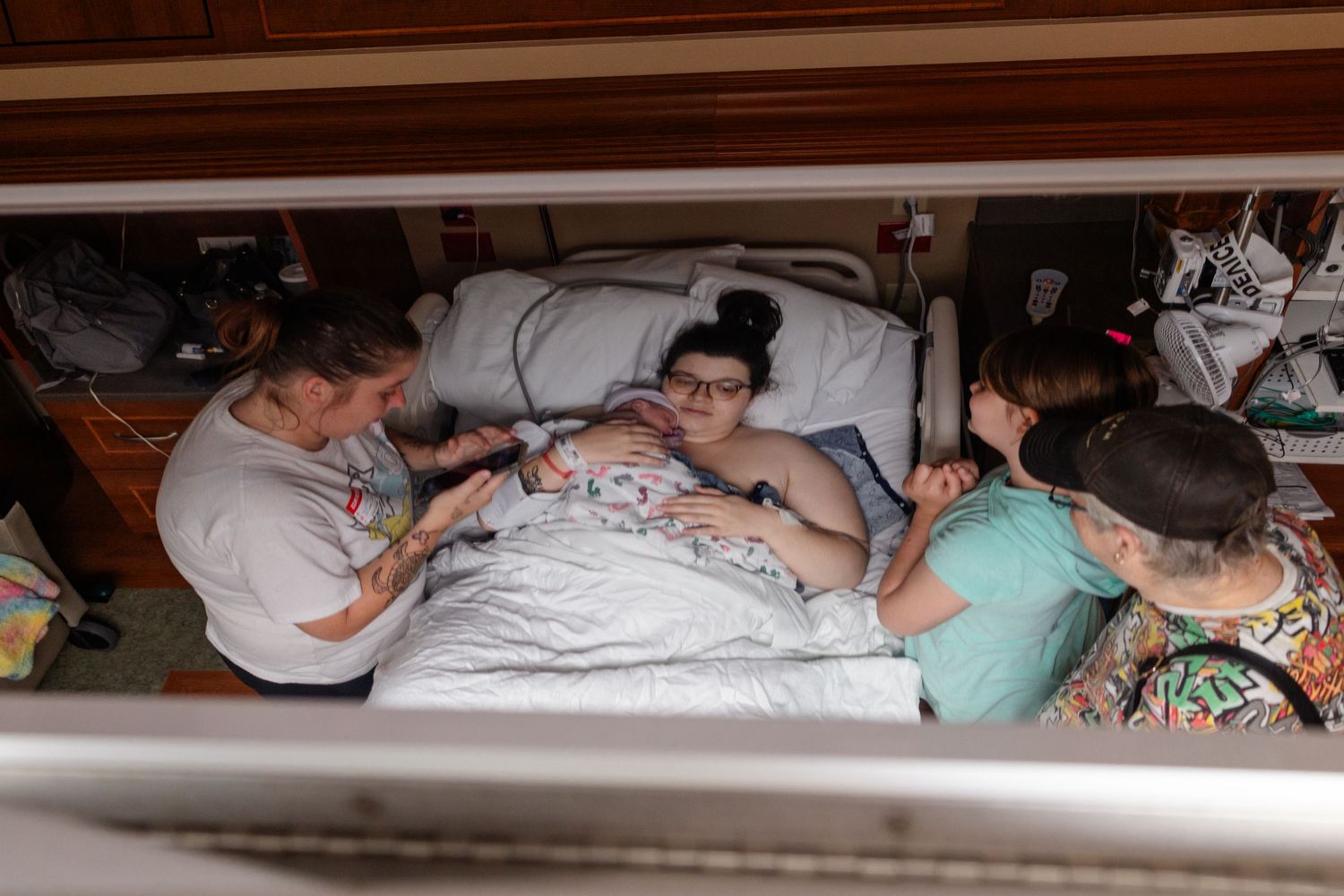 Creative photo shot through a ceiling mirror of a family visiting a new mother after birth in hospital room during labor.
