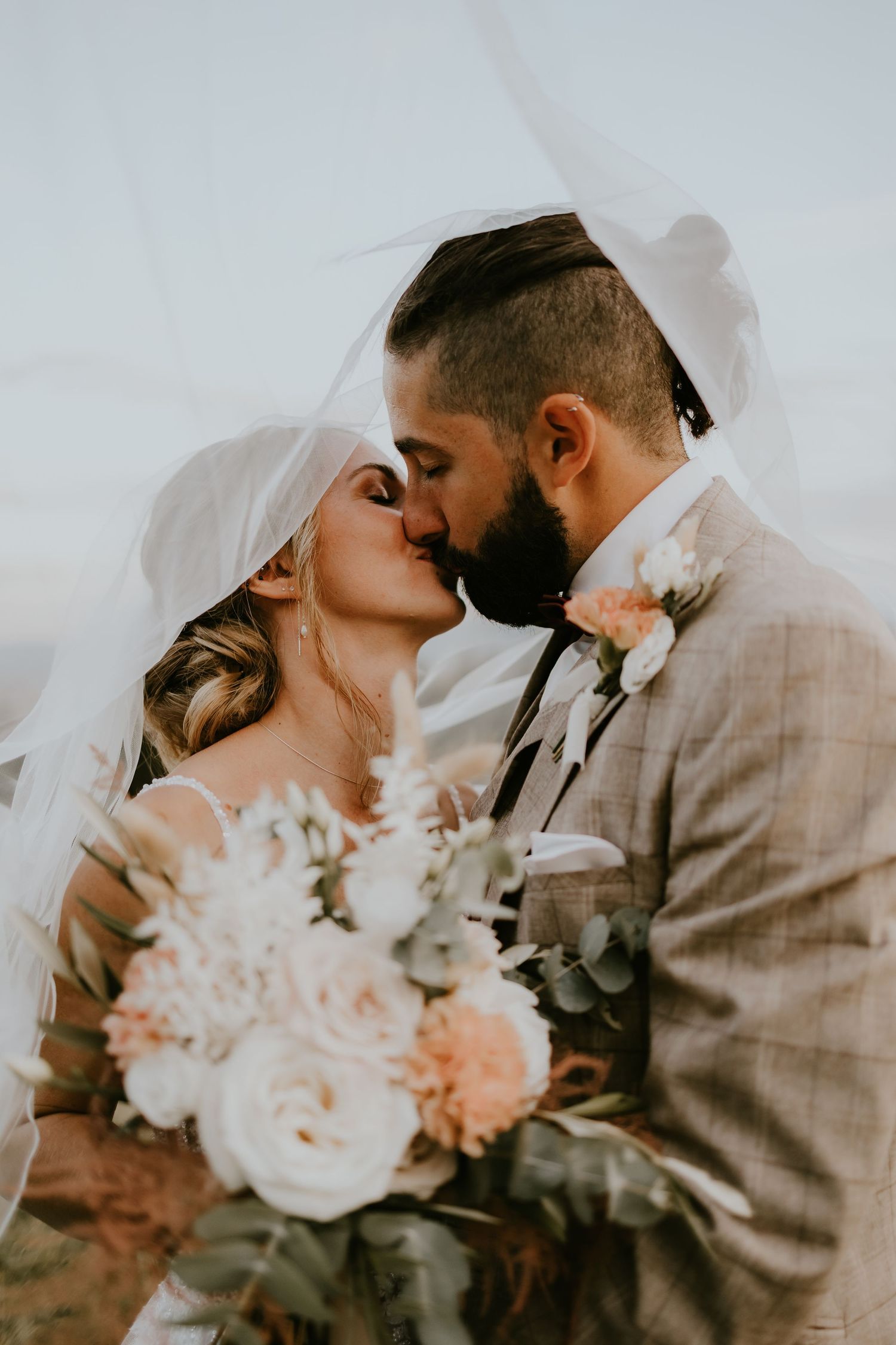 Brautpaar küsst sich unter dem Schleier bei ihrer Hochzeit im Berghotel Jägerhof in Isny im Allgäu
