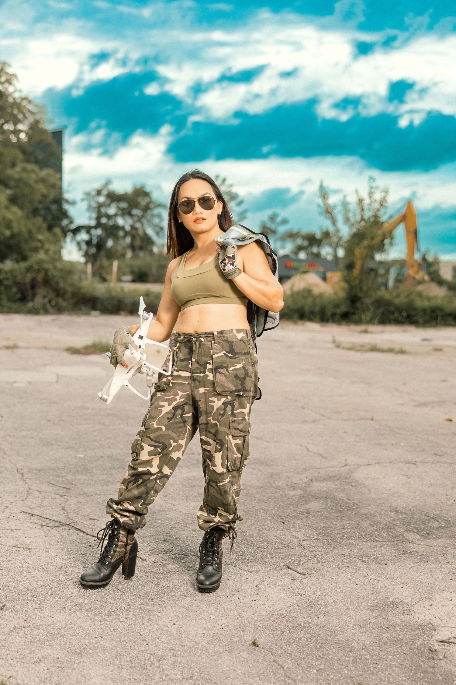 Outdoor fashion shoot with camouflage pants and combat boots against blue sky background.