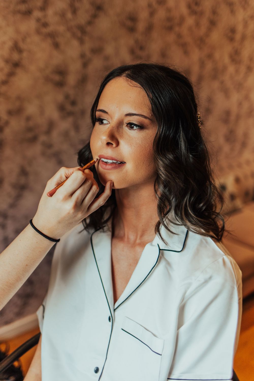 Wedding preparation scene with makeup application in white silk robe.