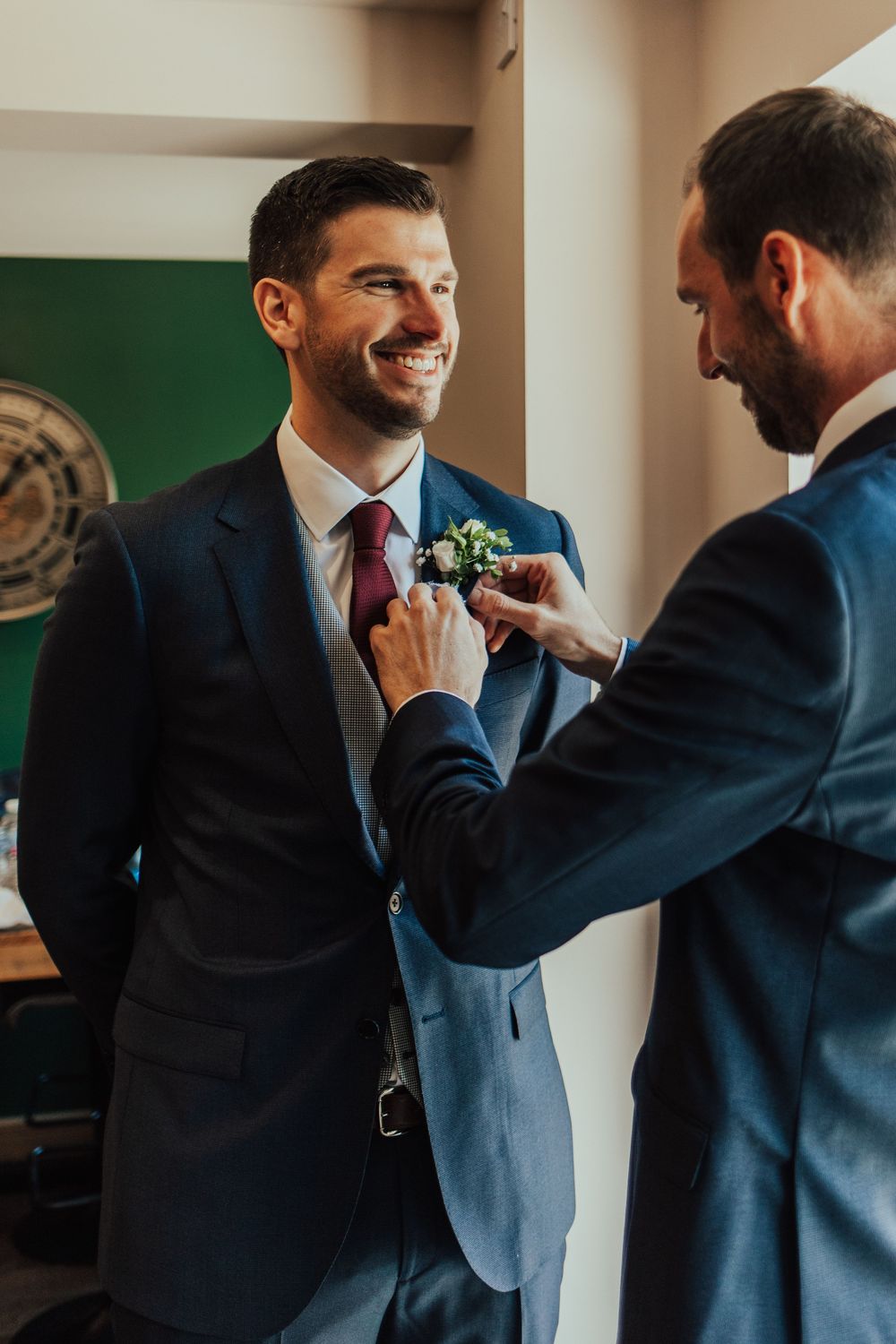 Groomsmen help adjust the groom's tie and boutonniere before the wedding ceremony.