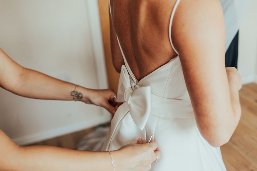 Close-up details of a white wedding dress with delicate straps and fabric textures.